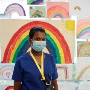 Nurse stands in front of pictures of rainbows
