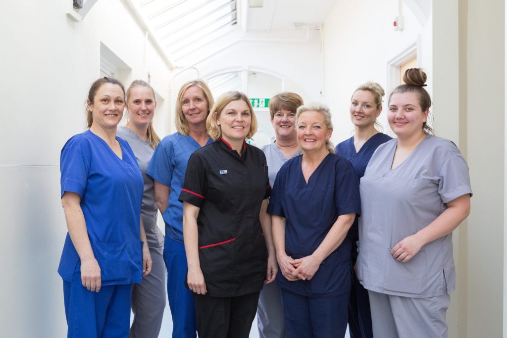 Eight (8) nurses standing together in hospital ward