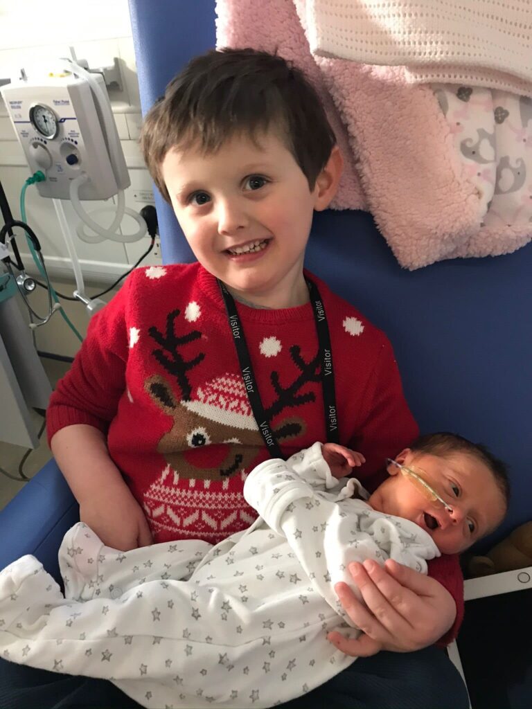 Big brother Albie holding Ava in NICU